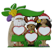 A decorative tropical-themed figurine featuring three cartoon characters under a palm tree: a Santa Claus figure with a white beard and green skirt holding a blank heart, a brown bear with glitter ears and a red hat holding a blank heart, and a woman with dark hair, a red hat, and a green skirt holding a blank heart. The figures are posed on a green base against a plain white background.