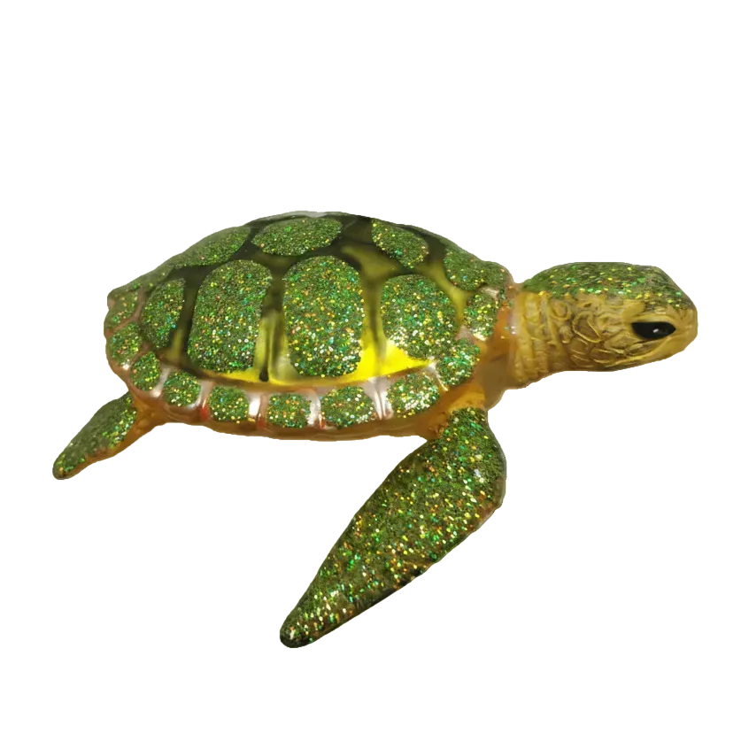 A glittery green sea turtle figurine with a gold-toned shell and head, isolated on a white background.
