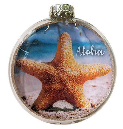 A round glass Christmas ornament featuring a printed beach scene with an orange starfish on sand and the word 'Aloha' in white script, topped with a silver cap.