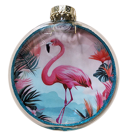A round clear glass ornament featuring a printed tropical design with a pink flamingo, palm leaves, and a glittery blue border, topped with a gold cap.