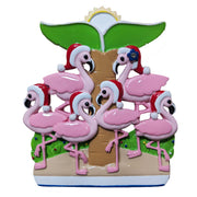 Decorative free-standing Christmas ornament with pink flamingos wearing Santa hats under a palm tree.